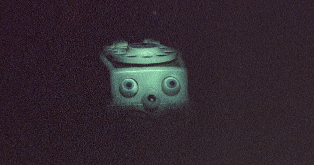 A dark, grainy image of a child's toy with large plastic eyes.